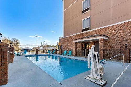 a swimming pool with chairs and a building at Comfort Inn & Suites Augusta West Near Fort Eisenhower in Augusta