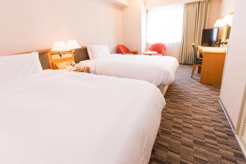 a hotel room with two beds and a desk at Hotel Sunroute Taipei in Taipei
