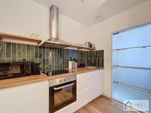 une cuisine avec une cuisinière et un micro-ondes dans l'établissement Petit Cocon - Confort & Moderne, à Dunkerque