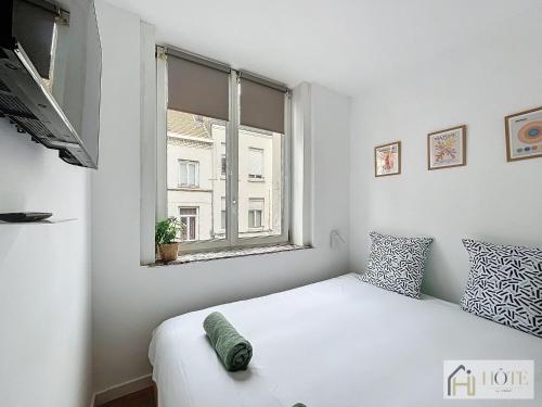 une chambre blanche avec un lit et une fenêtre dans l'établissement Petit Cocon - Confort & Moderne, à Dunkerque