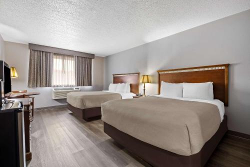 a hotel room with two beds and a television at Quality Inn near Monument Health Rapid City Hospital in Rapid City