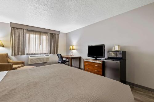 a hotel room with a bed and a flat screen tv at Quality Inn near Monument Health Rapid City Hospital in Rapid City
