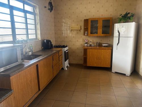 a kitchen with a white refrigerator and wooden cabinets at ALAMEDA iNN in Poços de Caldas