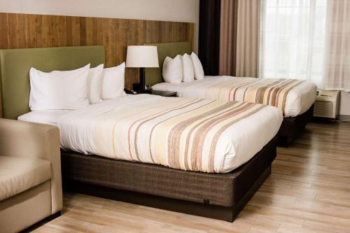 a hotel room with two beds and a chair at Country Inn & Suites by Radisson, Winchester, VA in Winchester