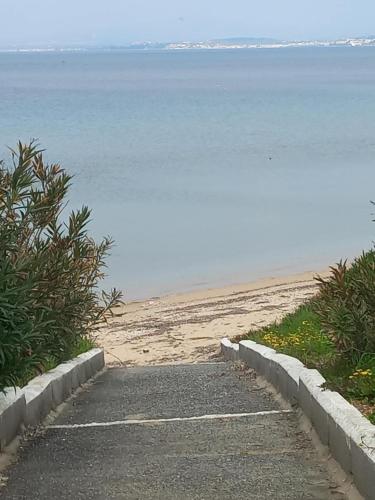 a path leading to a beach with the water at By the sea in Nea Potidaea