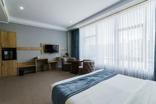 a hotel room with a bed and a television at Park Hotel al Bustan in Shymkent