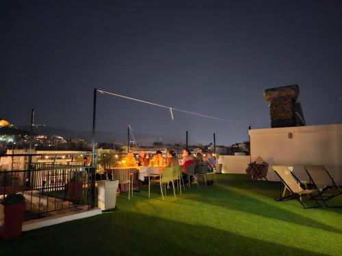 a group of people sitting at tables on a balcony at night at Lycabettus View Kaniggos in Athens