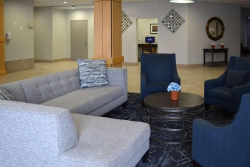 a waiting room with couches and chairs and a table at Suburban Studios East Syracuse Carrier Circle in East Syracuse