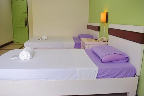 two beds in a room with purple and green walls at The Inns Bacolod in Bacolod