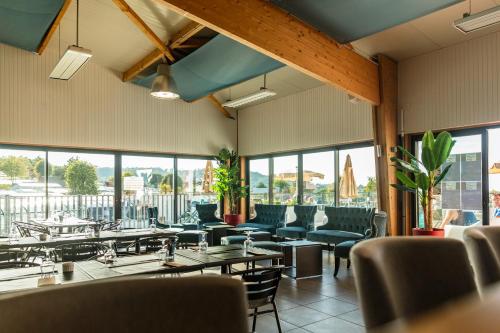 un restaurant avec des tables, des chaises et des fenêtres dans l'établissement Camping La Vallée, à Houlgate