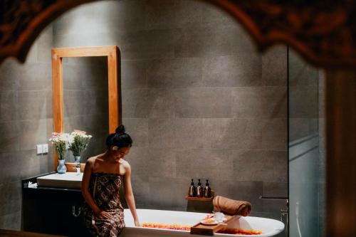 a woman standing in a bath tub in a bathroom at Sakti Garden Resort & Spa in Ubud