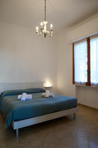 a bedroom with a bed with blue sheets and a chandelier at Villa Camilla Appartamento Giardino in Diano Castello