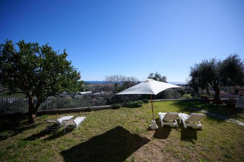 a group of chairs and an umbrella in the grass at Villa Camilla Appartamento Giardino in Diano Castello