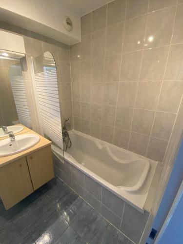 une salle de bain avec une baignoire et un lavabo dans l'établissement La Résidence St Arnould, À 10 min du centre de Strasbourg, à Schiltigheim