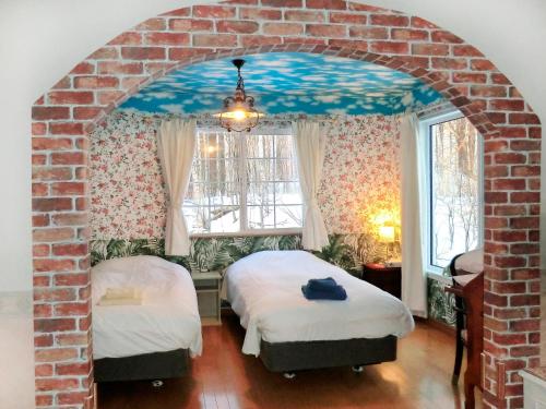 a bedroom with two beds and a brick wall at 丘の上白亜の洋館風別荘静かな小さなお宿Guest House Itoh 2名様から6名様 in Asahikawa