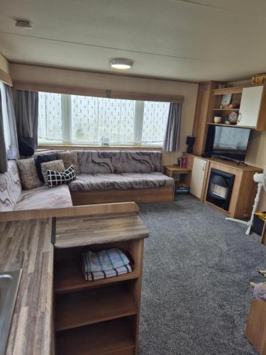 ein Wohnzimmer mit Sofa und Fernseher in der Unterkunft Woods caravan in Ingoldmells