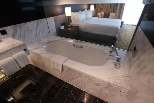 a bathroom with a bath tub and a bed at Hilton Bengaluru Embassy Manyata Business Park in Bengaluru