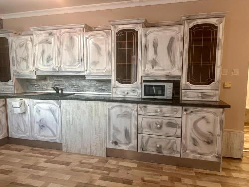 a kitchen with white cabinets and a microwave at Hotel Oppium Restaurant & Garden in Ruse
