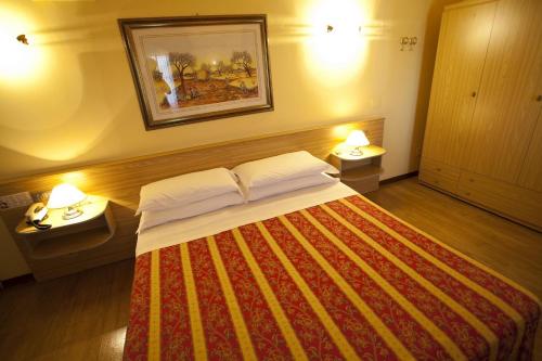 a bedroom with a bed with two night stands and two lamps at Albergo Nazionale in Salsomaggiore Terme