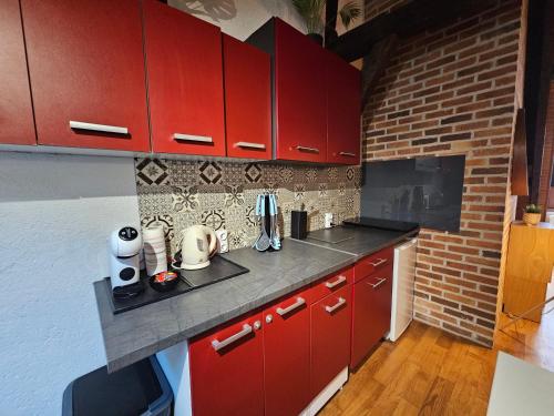 une cuisine avec des placards rouges et un mur en briques dans l'établissement Petit cocon chic et cosy, à Tours