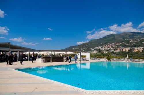a large blue swimming pool with a mountain in the background at Grand Hotel Moon Valley in Vico Equense