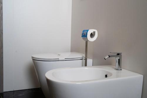 a white bathroom with a toilet and a roll of toilet paper at Pietra Viva Suite e Relax in Veglie