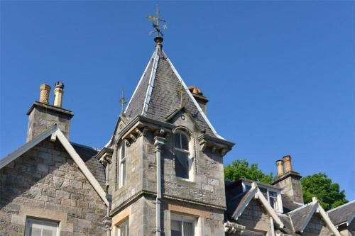 an old stone house with a cross on the roof at Wellwood Manor in Pitlochry