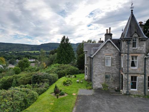 an old stone house with dogs in the yard at Wellwood Manor in Pitlochry