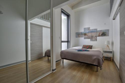 une chambre avec un lit et un grand miroir dans l'établissement Appartement Boulevard de la Plage, à Arcachon