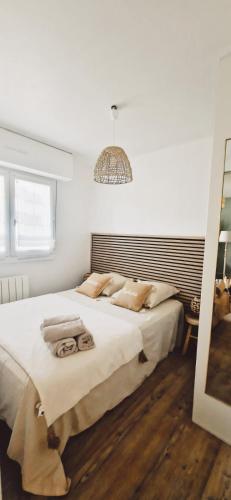 une chambre avec un grand lit blanc avec un lustre dans l'établissement Appartement cosy avec balcon 4 personnes max, à Villers-sur-Mer