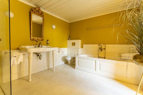 a bathroom with a sink and a tub and a toilet at Landgoed Loenen B&B in Slijk-Ewijk