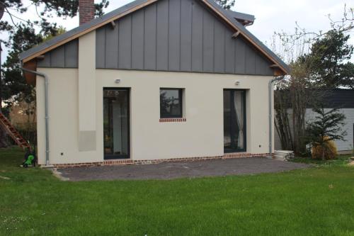 a white house with a black roof at L'idylle - maison a la mer in Quiberville