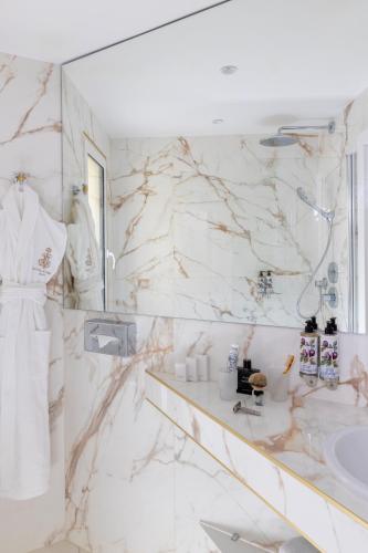 a white bathroom with a sink and a mirror at Hôtel Kleber Paris & Spa in Paris