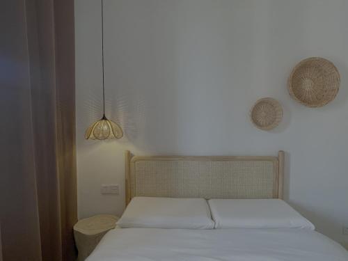 a bedroom with a bed with white sheets and a lamp at Island Flower Coconut 花椰椰民宿 in Haikou
