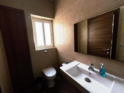 a bathroom with a sink and a toilet and a mirror at Slimiza Suites in Sliema