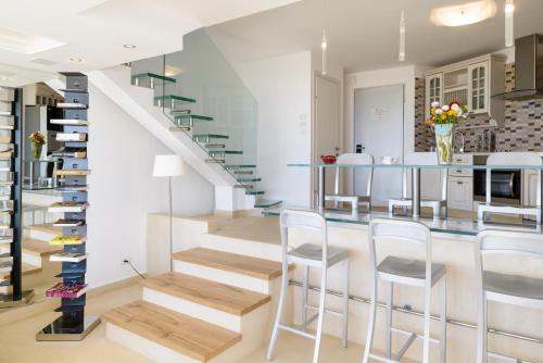 a kitchen with a staircase with white cabinets and white stools at Beach Duplex with 2 Terraces & Sea View by FeelHome in Herzliya Pituah
