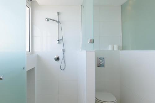a white bathroom with a shower and a toilet at Beach Duplex with 2 Terraces & Sea View by FeelHome in Herzliya Pituah