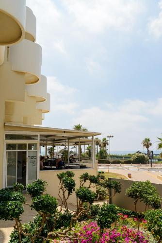 a building with trees and flowers in front of it at Beach Duplex with 2 Terraces & Sea View by FeelHome in Herzliya Pituah