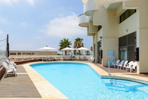 a pool at a hotel with chairs and umbrellas at Beach Duplex with 2 Terraces & Sea View by FeelHome in Herzliya Pituah