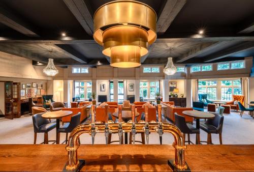 a restaurant with tables and chairs and a chandelier at Thatchers, BW Signature Collection in East Horsley