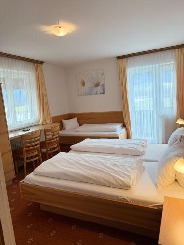 a hotel room with two beds and a table and chairs at Pension Plattenhof in Telfs