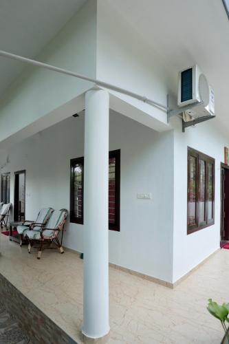 a room with white walls and chairs and a pillar at Marari John Villa in Mararikulam