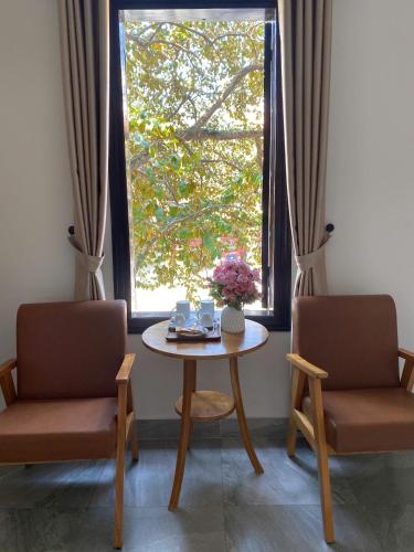 a table and two chairs in a room with a window at Lavande Hue Homestay in Hue