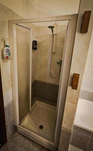 una ducha con puerta de cristal en un baño en Tiriticco B&B, en Podenzano