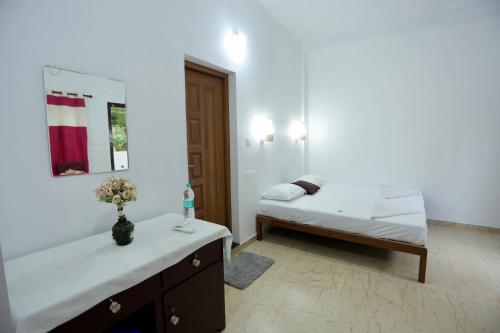 a white room with a bed and a mirror at Marari John Villa in Mararikulam