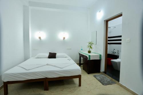 a bedroom with a bed and a sink and a mirror at Marari John Villa in Mararikulam