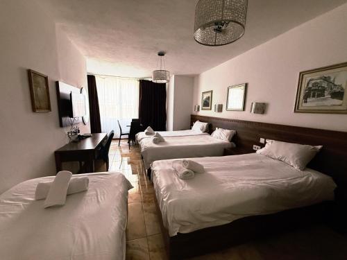 a hotel room with three beds and a desk at Slimiza Suites in Sliema