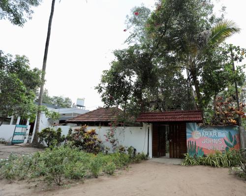 a small white building with a tree above it at Marari John Villa in Mararikulam