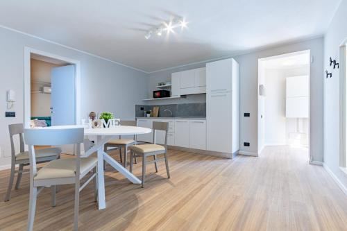a kitchen and dining room with a white table and chairs at ComoLake Apartments & Rooms in Cantù