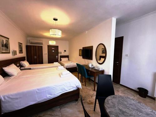 a hotel room with two beds and a desk and a table at Slimiza Suites in Sliema